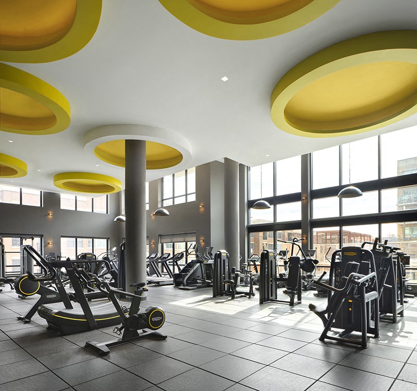 a gym with cardio equipment and windows in a building