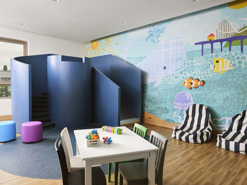 a childs playroom with a table and chairs and a wall with a mural