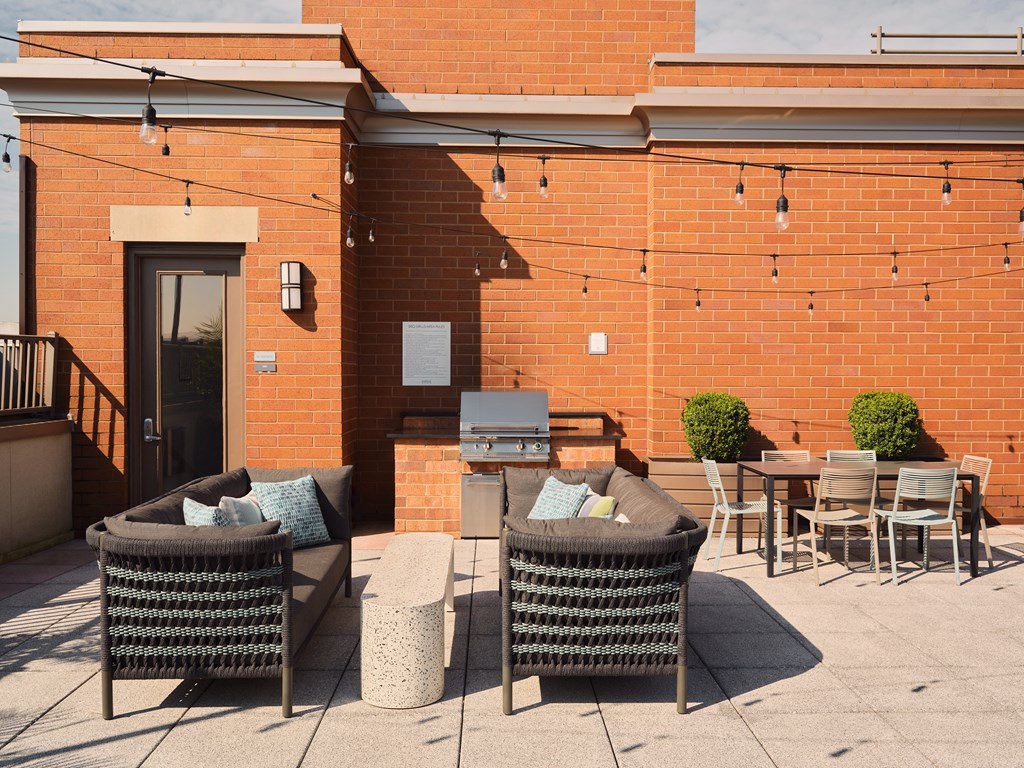 a patio with chairs and tables in front of a brick building