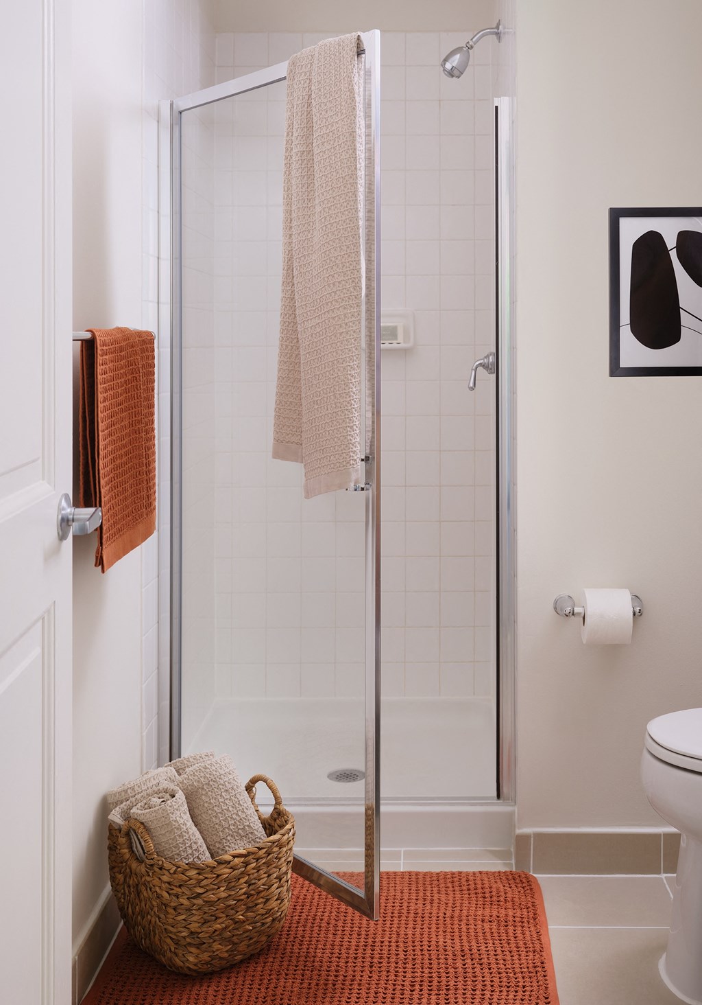 a small bathroom with a shower and a basket of towels