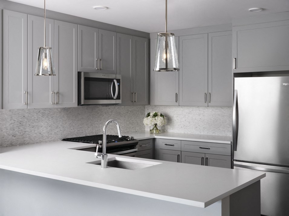 a white kitchen with stainless steel appliances and white counter tops