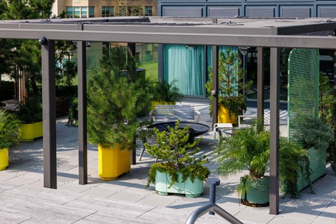 A patio with a roof and a variety of potted plants.