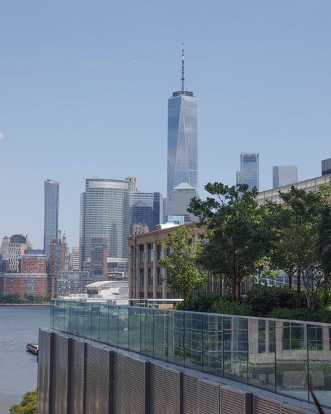 A cityscape with a river in the foreground and a tall skyscraper in the background.