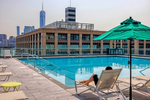 A woman is sunbathing by a pool on a sunny day.