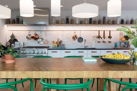 A kitchen with a wooden table and green chairs.