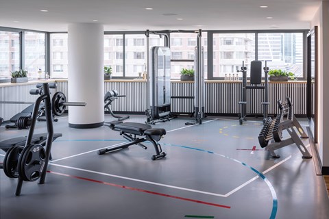 A gym with a variety of equipment including weights and a bench.