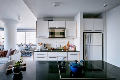A modern kitchen with a black countertop and white cabinets.