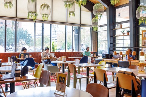 A group of people are sitting at tables in a brightly lit restaurant.