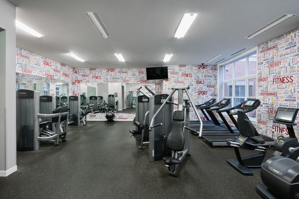 a gym with treadmills and other exercise equipment and a wall filled with wallpaper