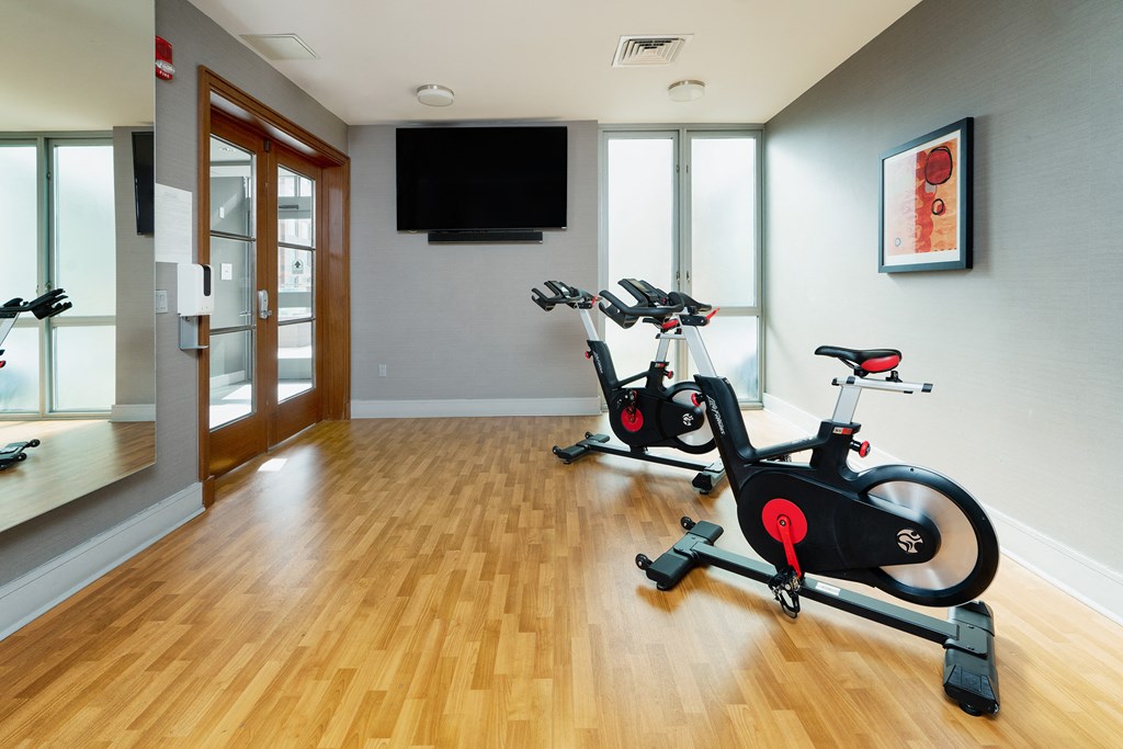 a gym with two exercise bikes and a tv on the wall