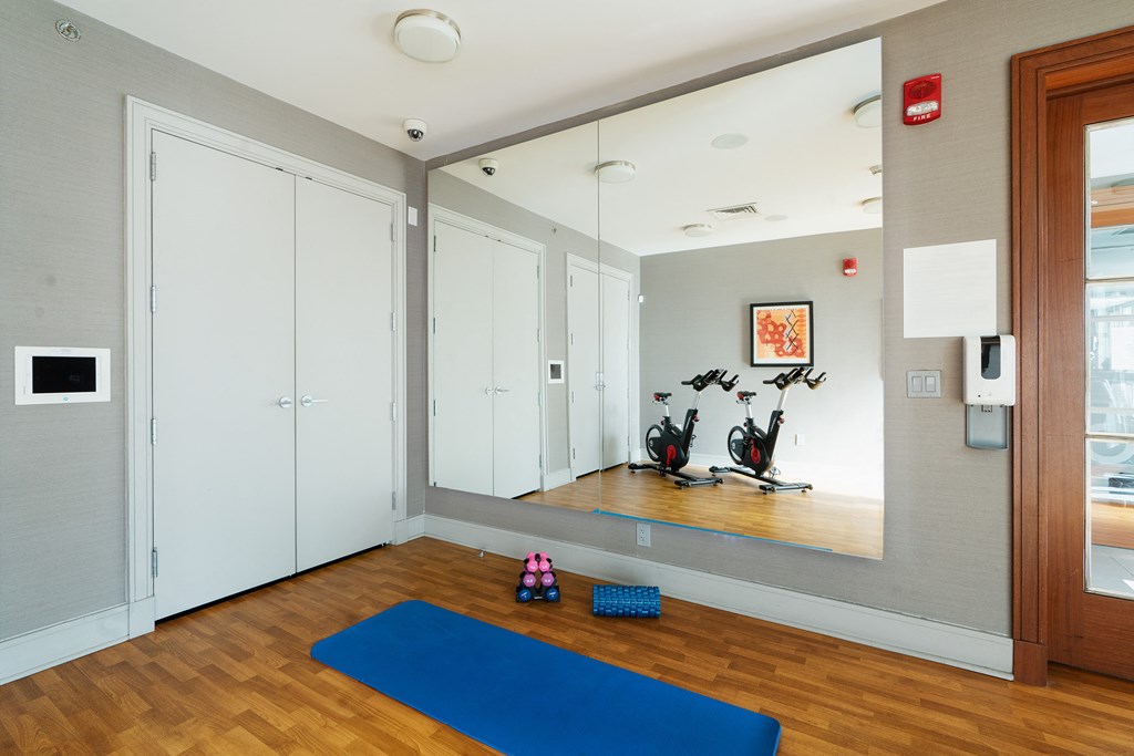 a yoga room with a blue mat and a wall mounted mirror