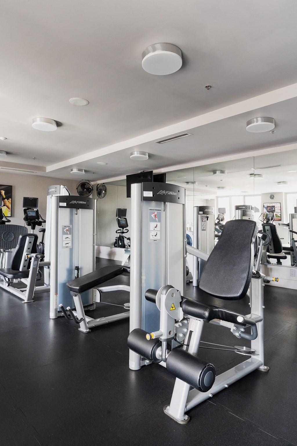 a gym with cardio machines and weights on a black floor