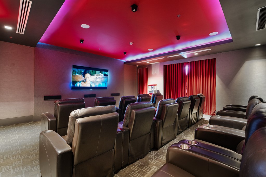 a movie theater with brown leather chairs and a red projector screen