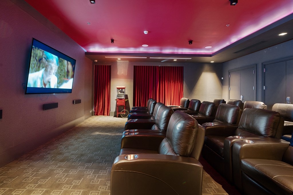 a home theater room with leather chairs and a tv