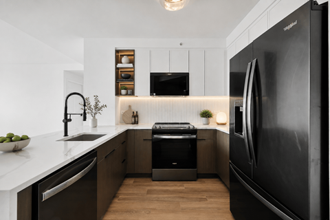 A modern kitchen with a black refrigerator and wooden floors.