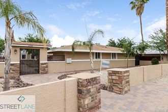 a house with a driveway and palm trees in front of it