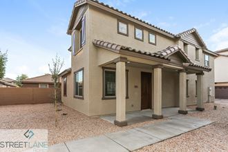 a beige home with columns and a sidewalk