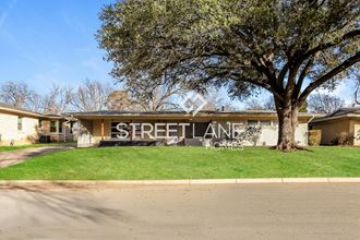 a street sign in front of a house with a tree