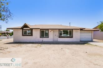 a small white house with a dirt road in front of it