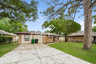 a small brick house with a sidewalk and a tree