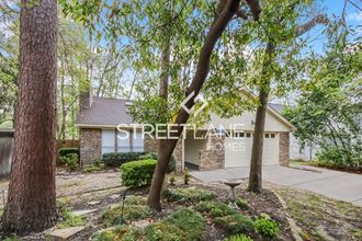 a home with a driveway and trees in front of it