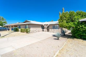 a home with a driveway and a house with a cactus