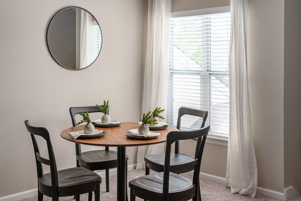a dining room with a table and chairs and a mirror