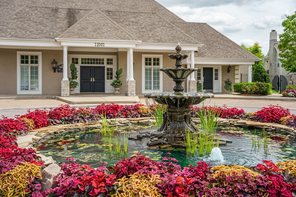 a fountain in a garden in front of a house
