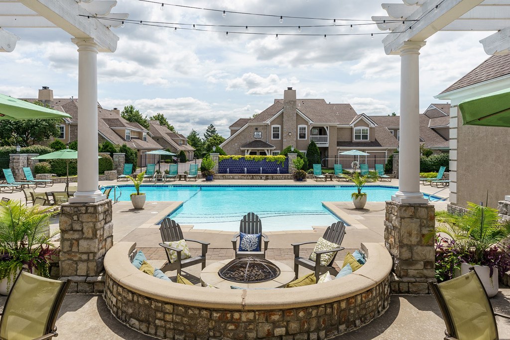 a swimming pool with chairs and umbrellas and a house in the background