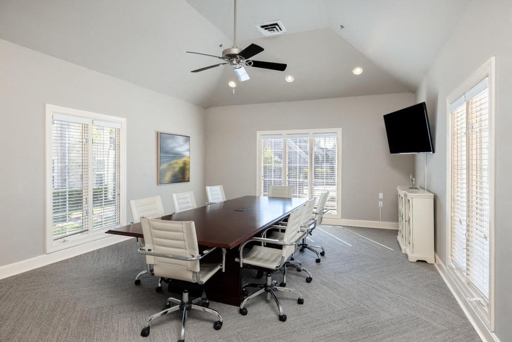 a conference room with a table and chairs and a ceiling fan