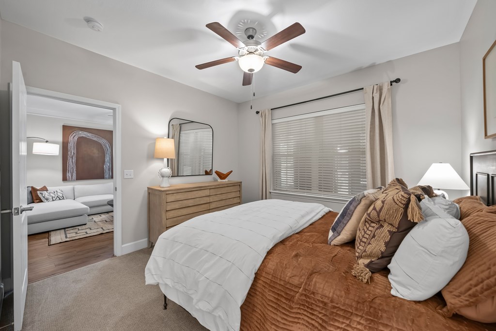 A bedroom with a bed, a dresser, and a ceiling fan.