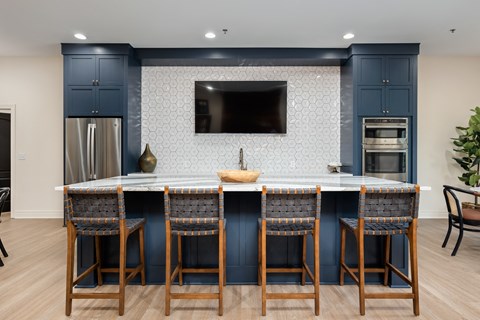 a large kitchen with blue cabinets and a marble counter top with four stools