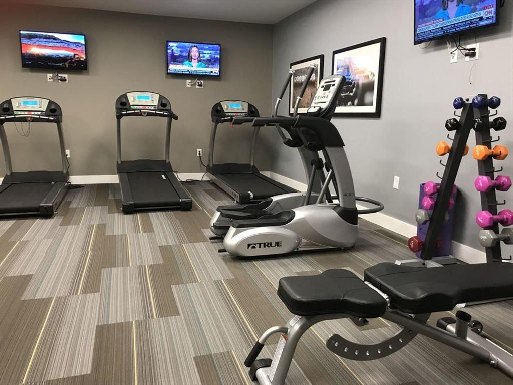 a gym with various machines and televisions on the wall