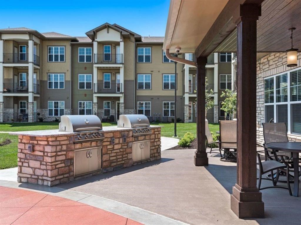 an outdoor kitchen with a grill and a patio in front of an apartment building