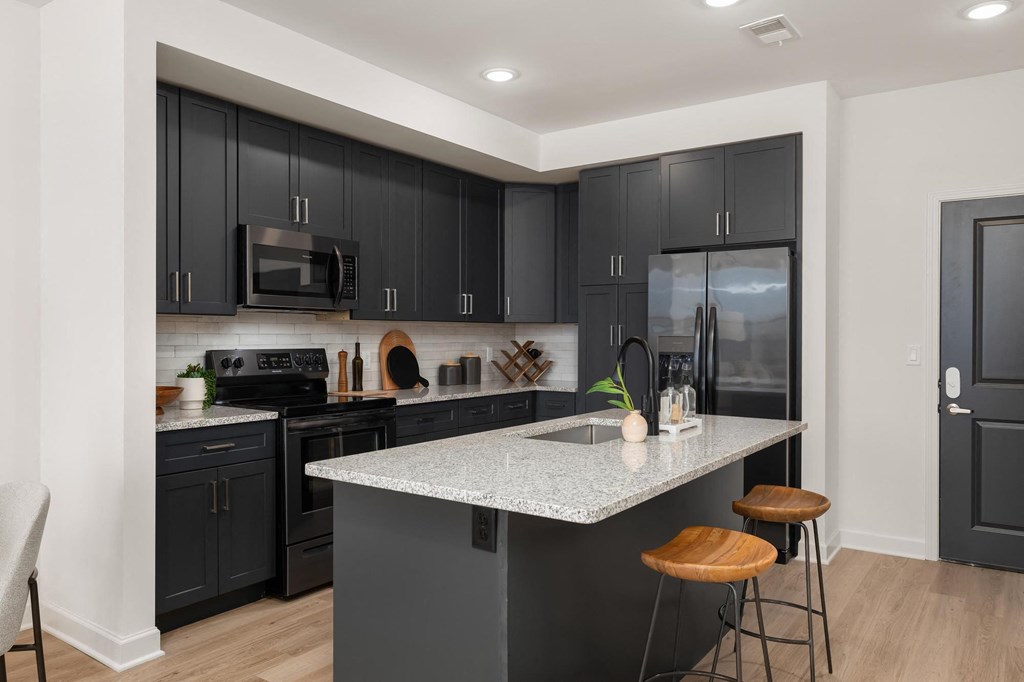 a kitchen with a marble counter top and black cabinets