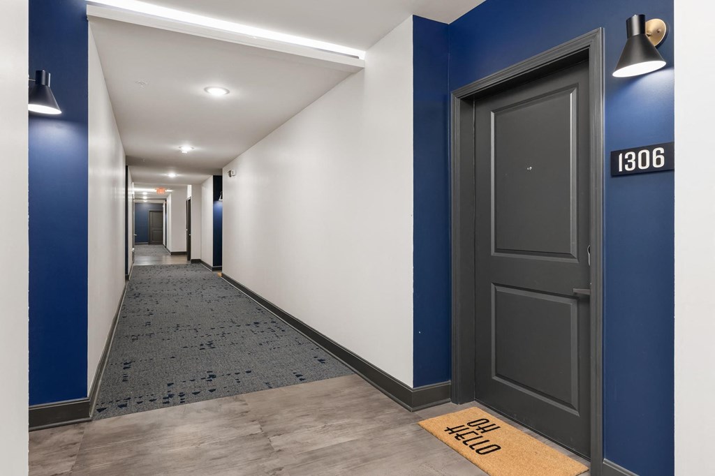 a corridor in a building with blue and white walls and a black door