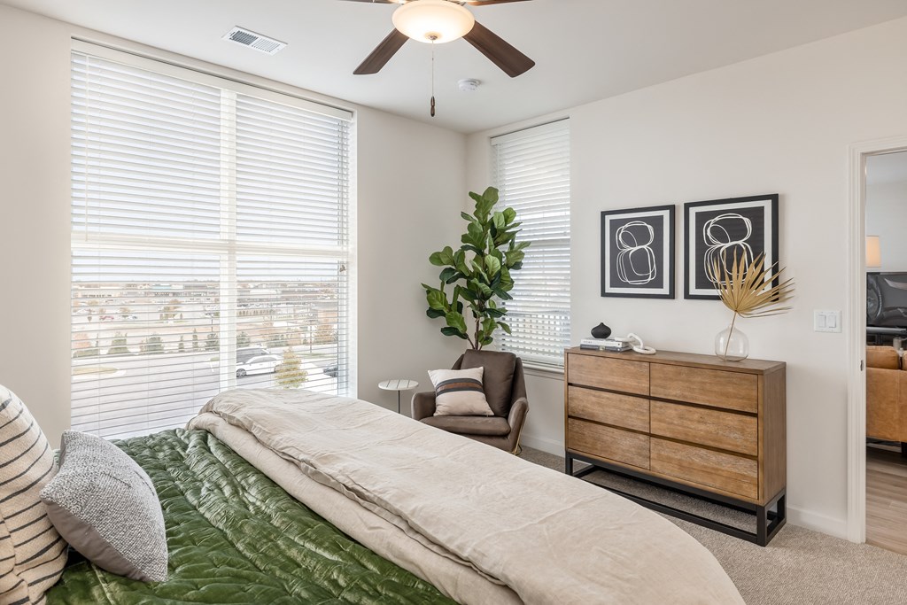 a bedroom with a large window and a ceiling fan
