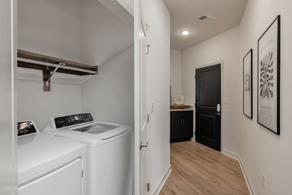 a laundry room with a washer and dryer and a door to a bathroom