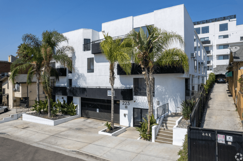 a white apartment building with palm trees in front of it