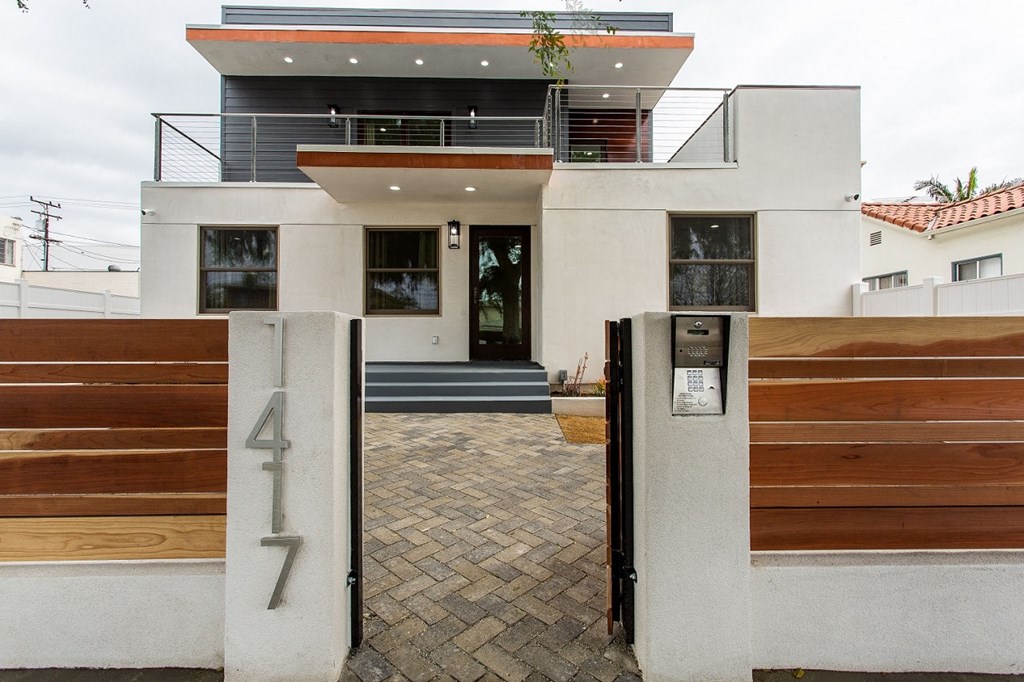 the front of a house with a driveway and a wooden gate