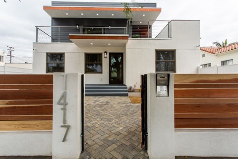 the front of a house with a driveway and a wooden gate