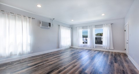 an empty living room with white walls and wood floors