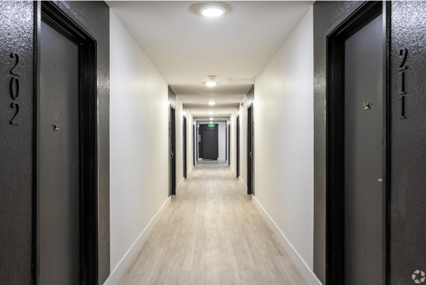 a long corridor with black doors and white walls and a wooden floor