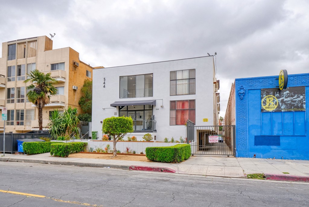 the exterior of a building with a blue and white facade and a sidewalk