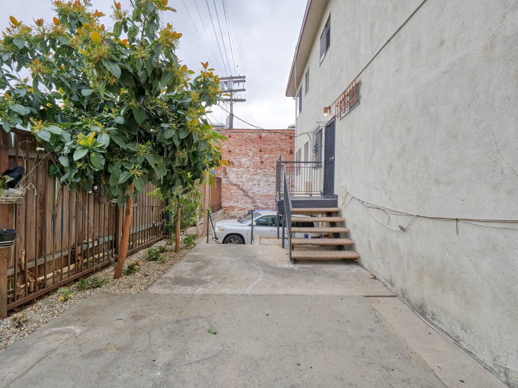 a small alley with stairs and a fence and a car in the distance