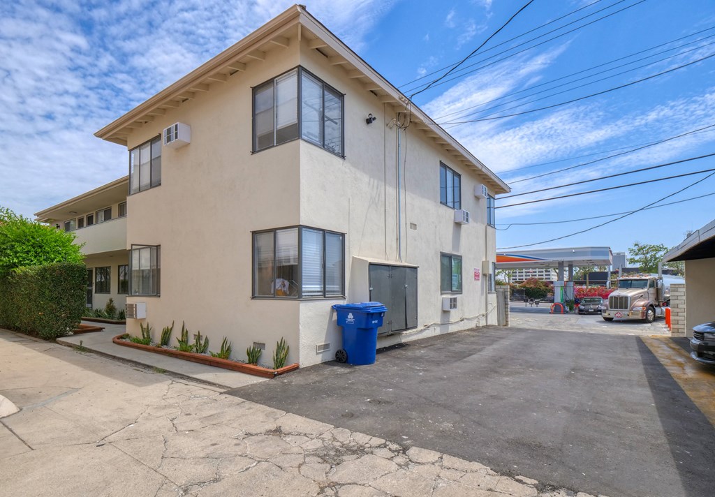 a white building with a blue trash can in front of it