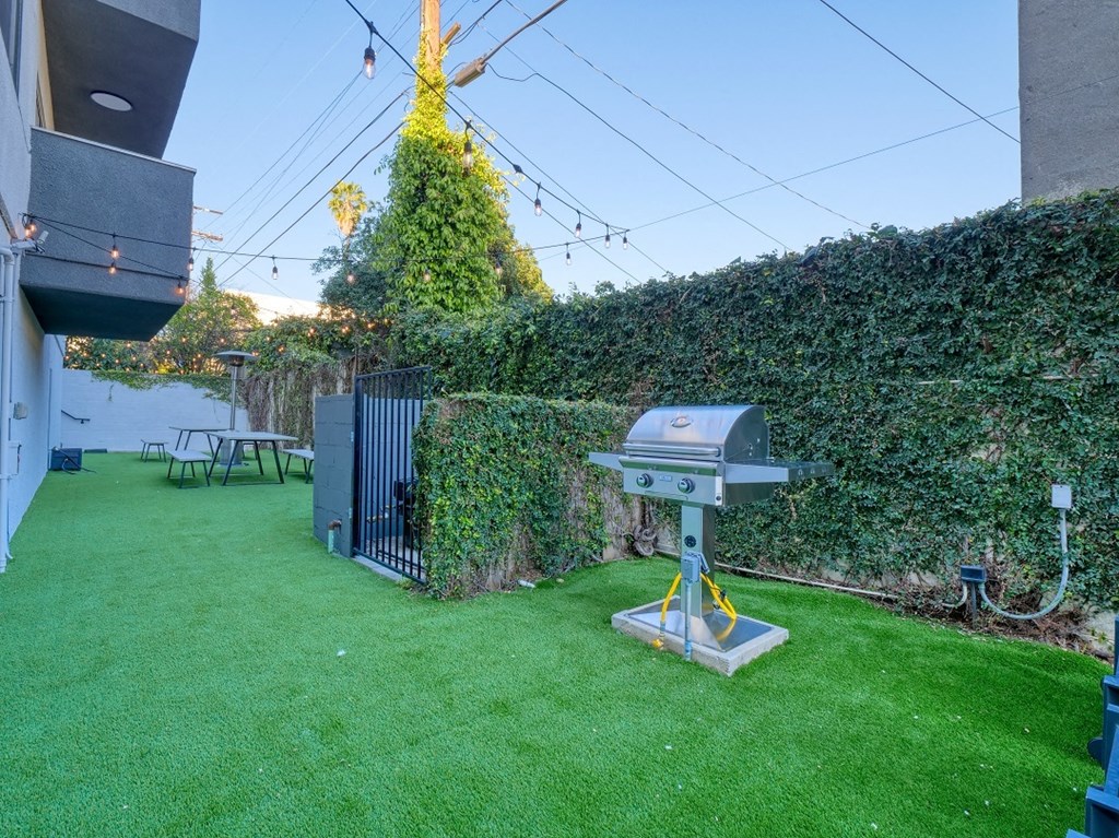 a backyard with a grill and a green lawn