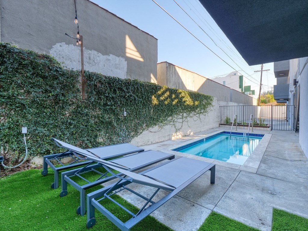the pool is adjacent to the house and has three picnic tables