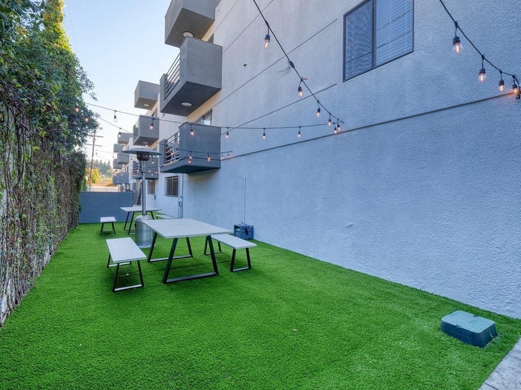 a backyard with picnic tables and a blue building with green grass