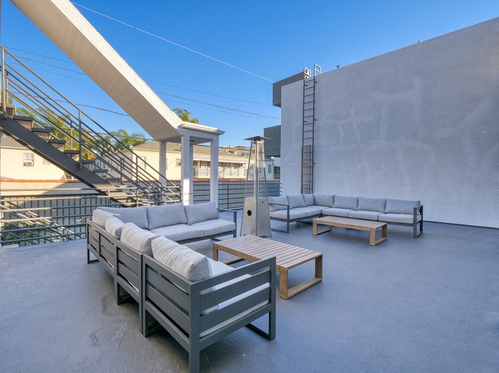 furnished patio with couches and tables on top of a building